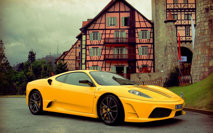 Yellow Ferrari Scuderia parked in front of a European-style building