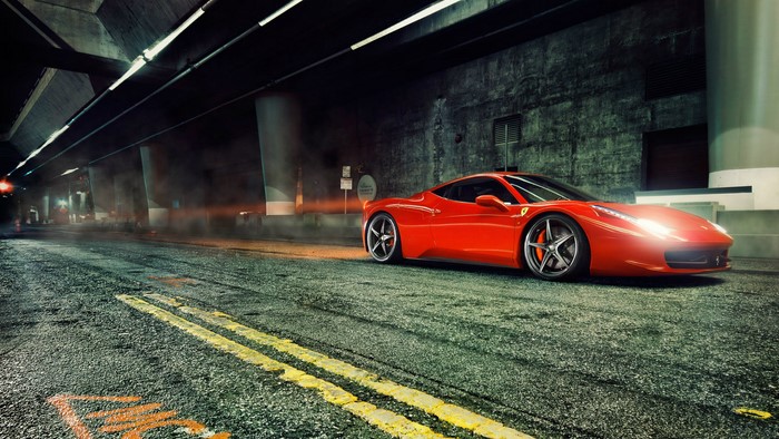 Red Ferrari 458 Italia parked on wet road under bridge