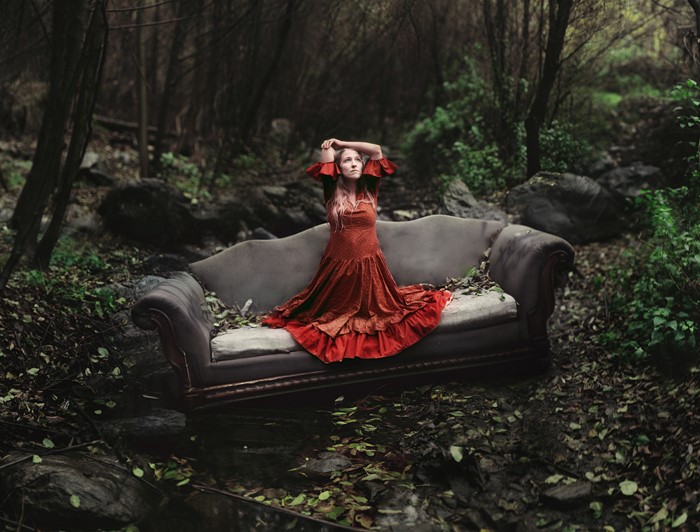 Woman in red dress on a couch in a forest