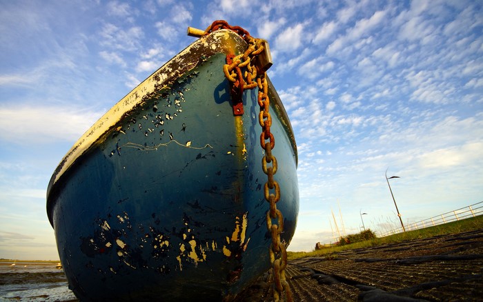 Blue boat with rusty chain on shore