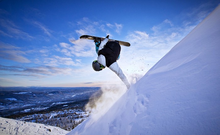Snowboarder performing a flip on a snowy mountain