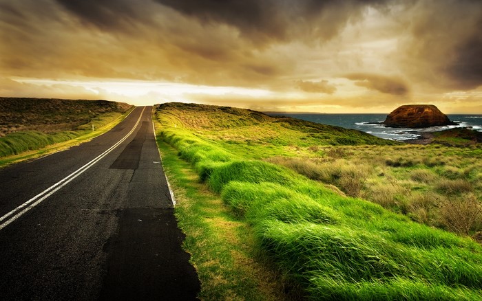 Road leading to the ocean with a rock formation