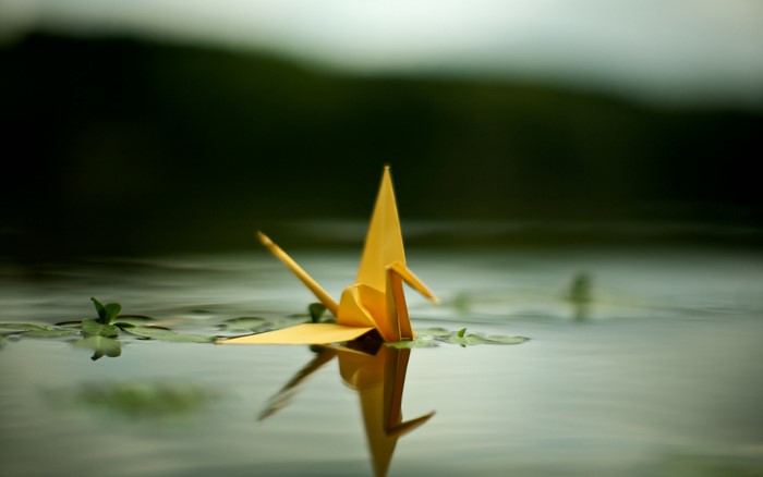 Yellow origami crane floating on water