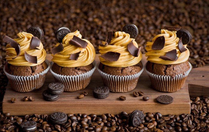 Four chocolate cupcakes with peanut butter frosting and chocolate shavings