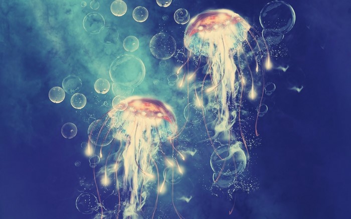 Two glowing jellyfish and bubbles in blue water