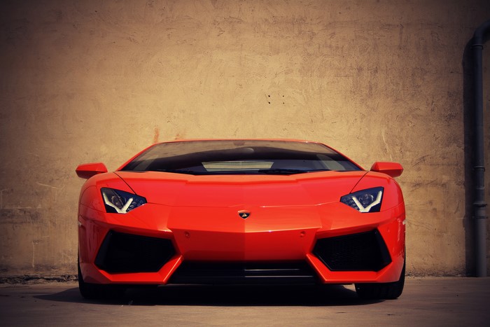 Orange Lamborghini Aventador parked against a wall