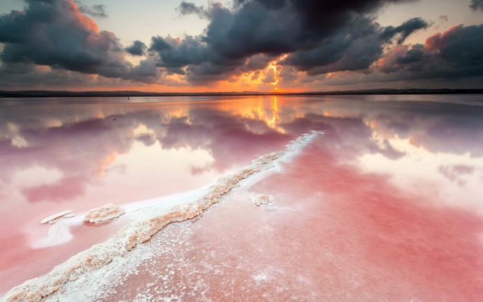 Pink salt lake at sunset with dramatic clouds