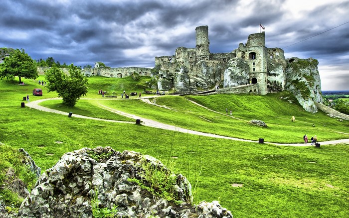 Castle ruins on a grassy hill under a cloudy sky