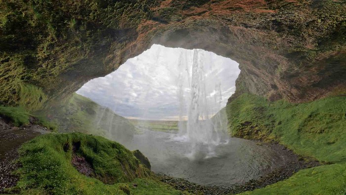 Waterfall behind a cave entrance