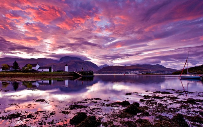 Sunset over a Scottish loch with mountains and a sailboat