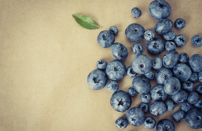 Blueberries and a leaf on a brown background