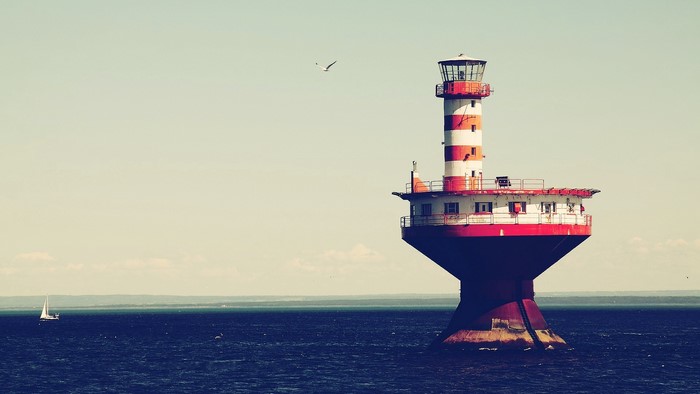 Lighthouse in the ocean with a sailboat