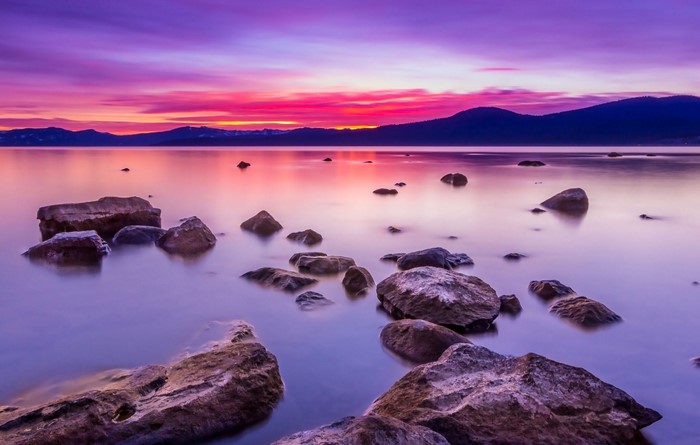 Rocky lake shore at sunset with purple and pink sky