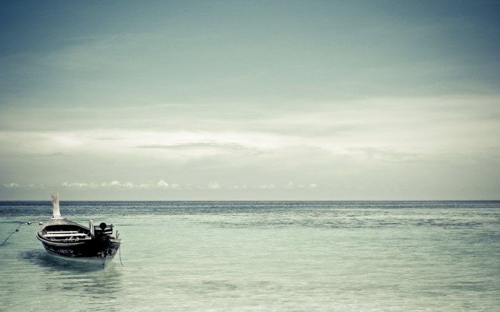 Boat floating on the ocean under a cloudy sky