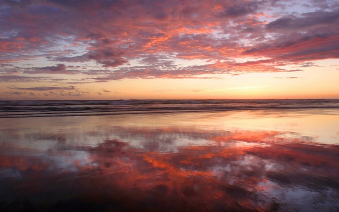 Sunset reflection on a beach with colorful clouds