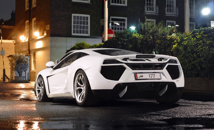 White McLaren sports car on wet street at night