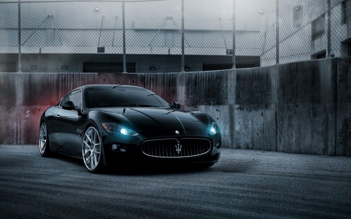 Black Maserati GranTurismo parked near a concrete wall