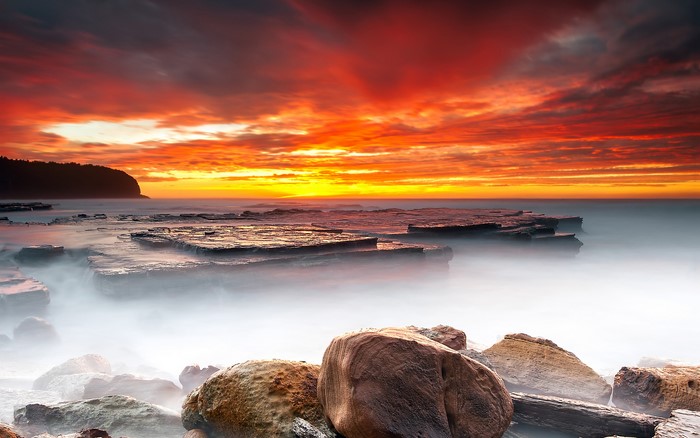 Sunset over rocky coastline with ocean mist