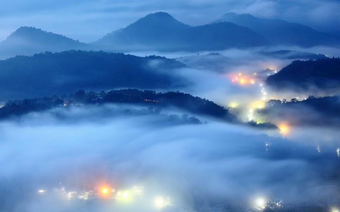 Mountains shrouded in fog with village lights
