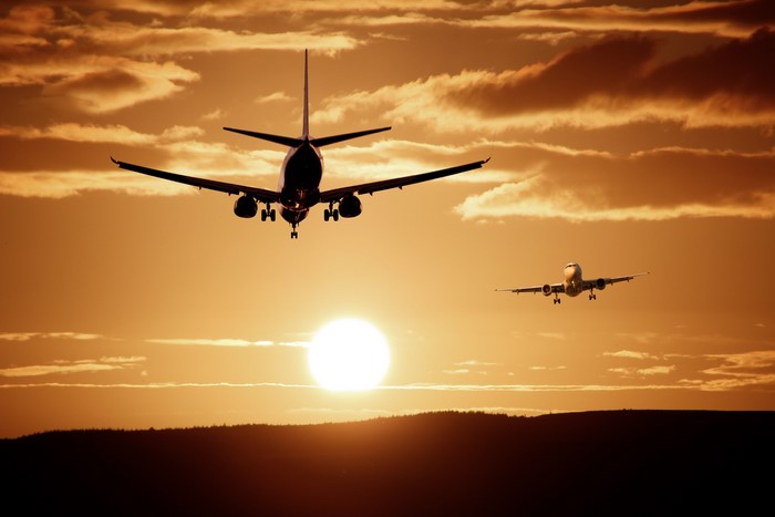 Two airplanes flying at sunset