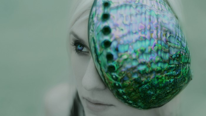 Woman with abalone shell covering her face