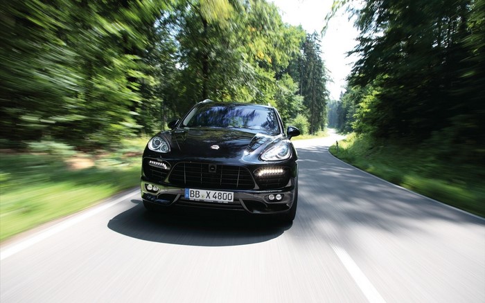 Black Porsche Cayenne driving on a forest road