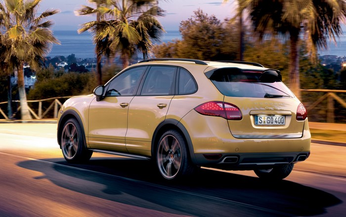 Yellow Porsche Cayenne driving on a road at dusk