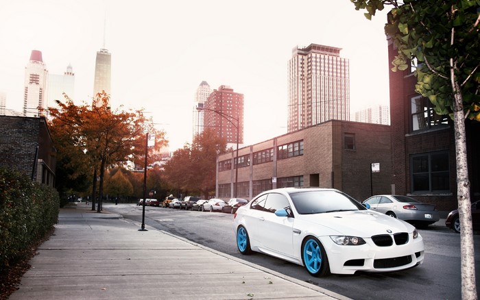 White BMW with blue rims on city street