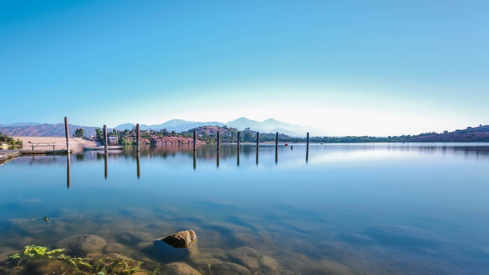 Wooden posts in a calm lake with mountains in the background