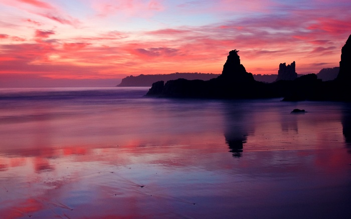 Sunset over a rocky coastline with reflections