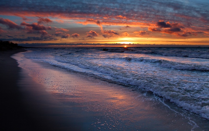 Sunset over the ocean with colorful clouds and waves