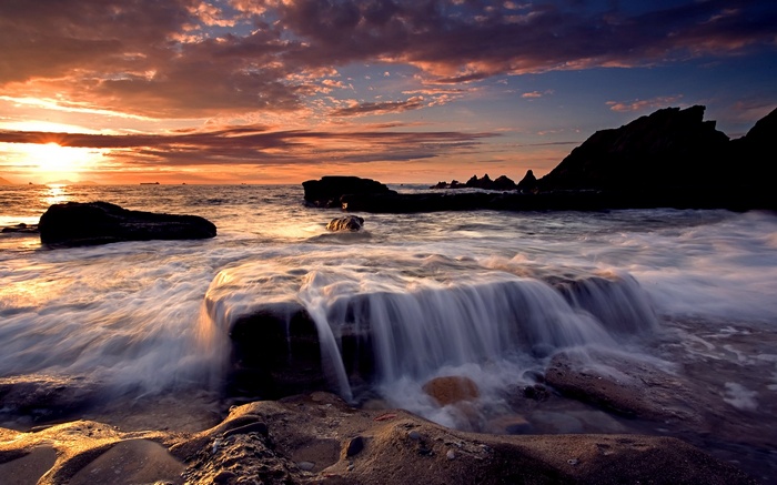 Ocean waves crashing on rocks at sunset