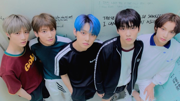 TXT members posing against a graffiti-covered wall