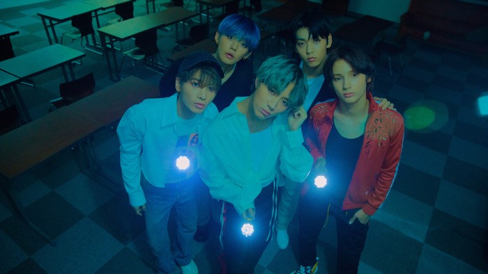 Five young men holding flashlights in a classroom