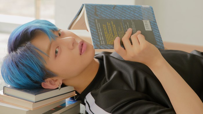 Person with blue hair reading a book