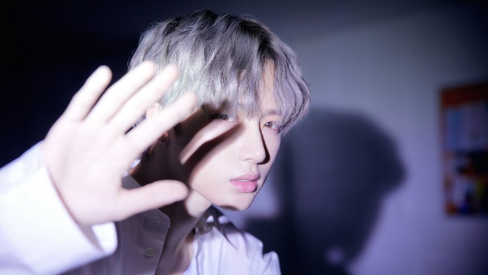 Man with silver hair covering face with hand