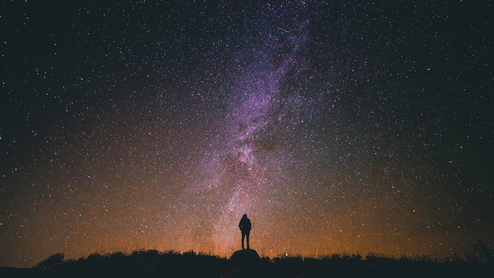 Person standing under the Milky Way galaxy