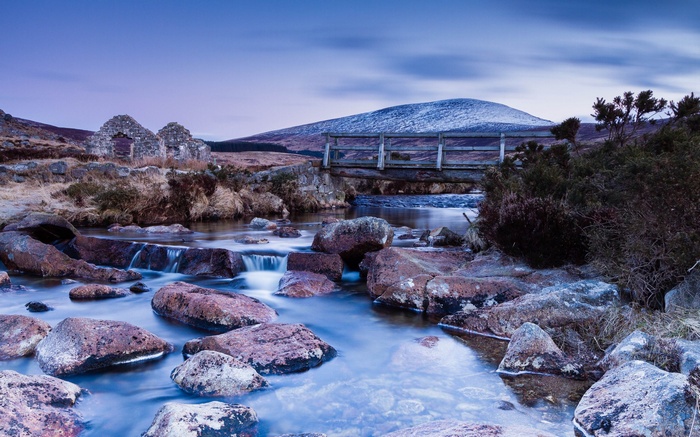 Stone ruins and wooden bridge over a rocky stream