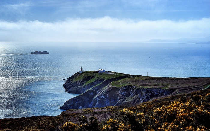 Ferry and lighthouse on a cliff overlooking the sea