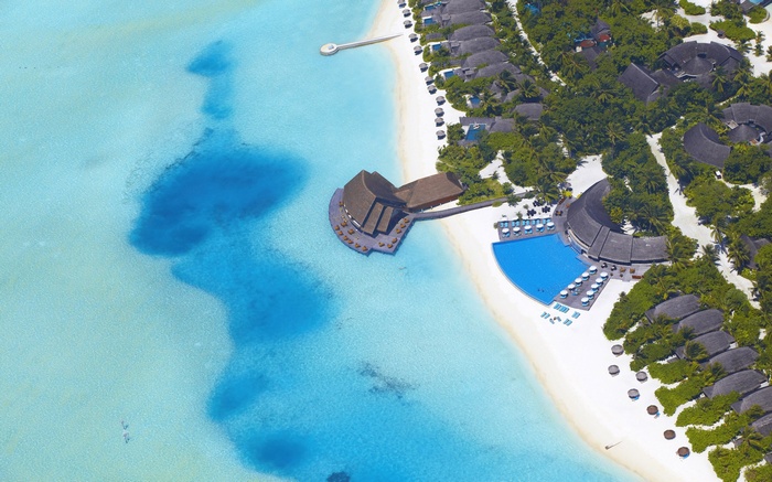 Aerial view of a tropical resort with overwater bungalows and a swimming pool