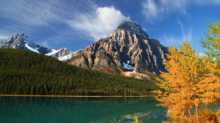 Mountain lake with autumn trees and snowy peaks