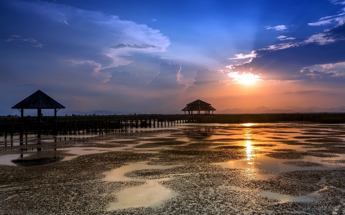 Gazebos on a boardwalk over a marsh at sunset