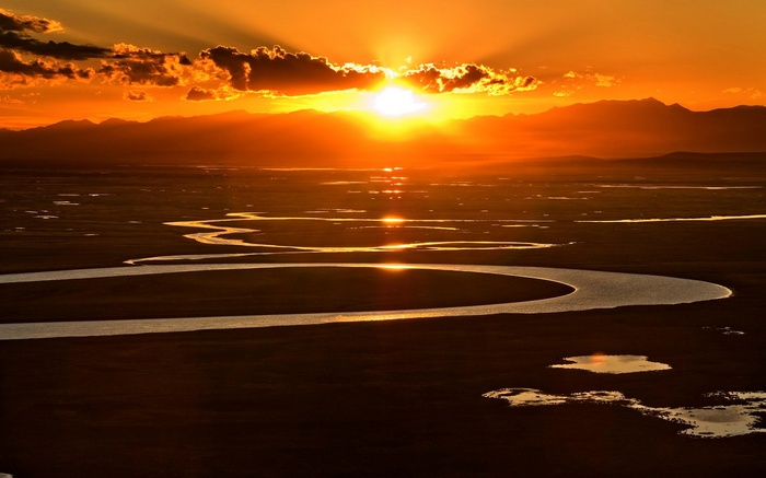 Sunset over a winding river and mountains