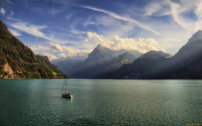 Sailboat on a lake with mountains and clouds
