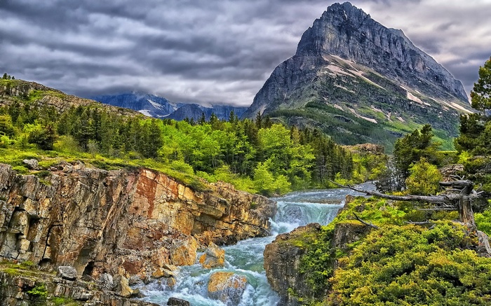 Mountain stream flowing through a rocky gorge with a large mountain peak