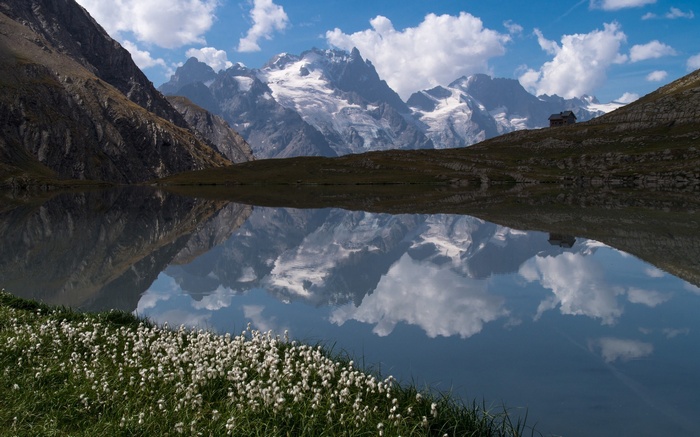 Mountain lake reflecting snow-capped peaks and a small cabin