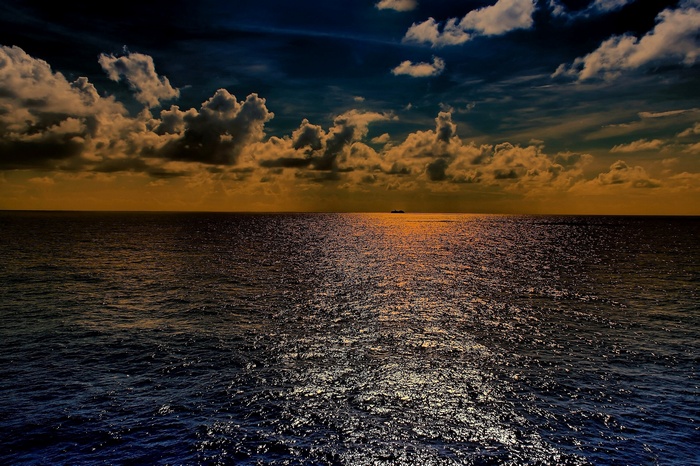 Ship on the ocean at sunset with dramatic clouds