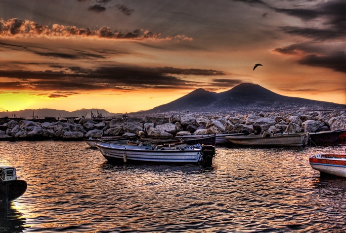 Boats in harbor with Mount Vesuvius at sunset