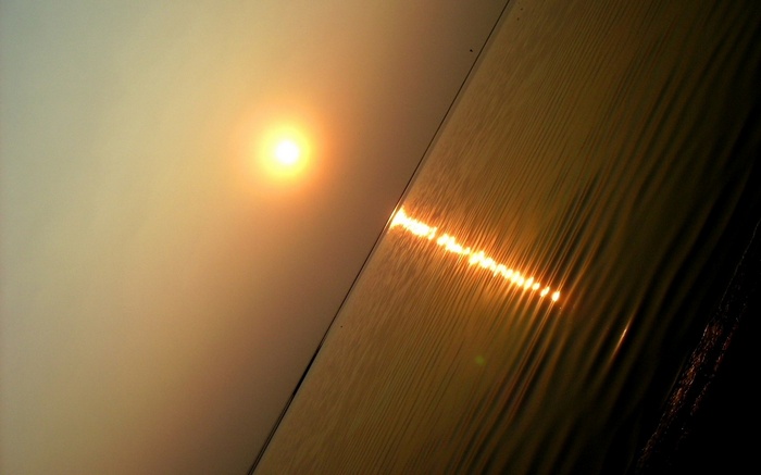 Sun setting over rippling water with reflection