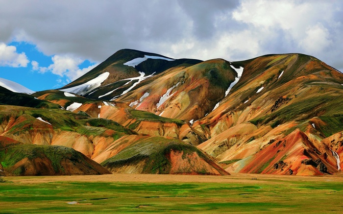 Colorful mountains with snow patches and green meadow